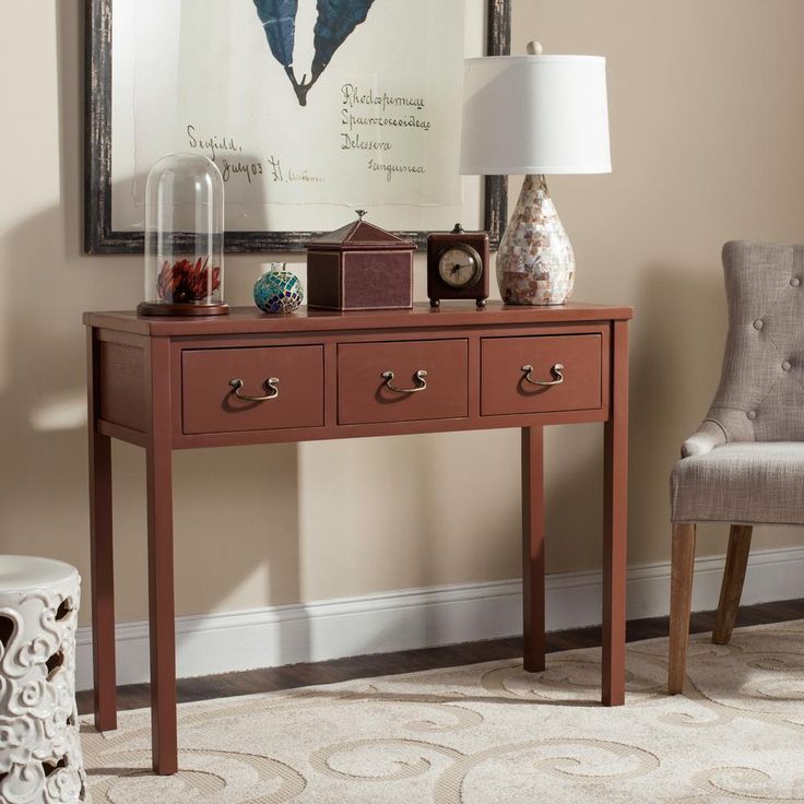 a table with two drawers and a lamp on it in front of a framed poster