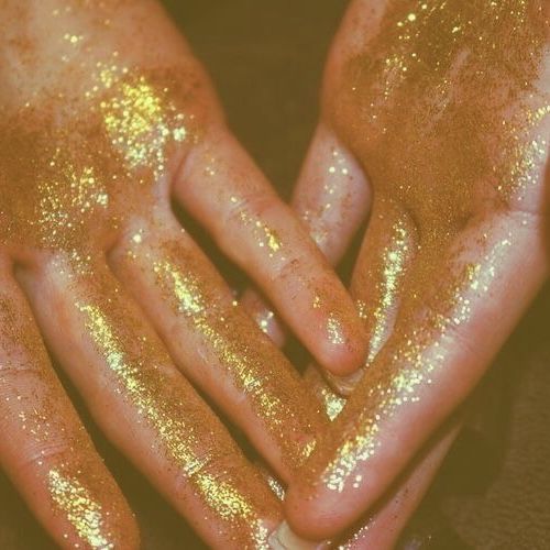 two hands are covered with yellow glitter