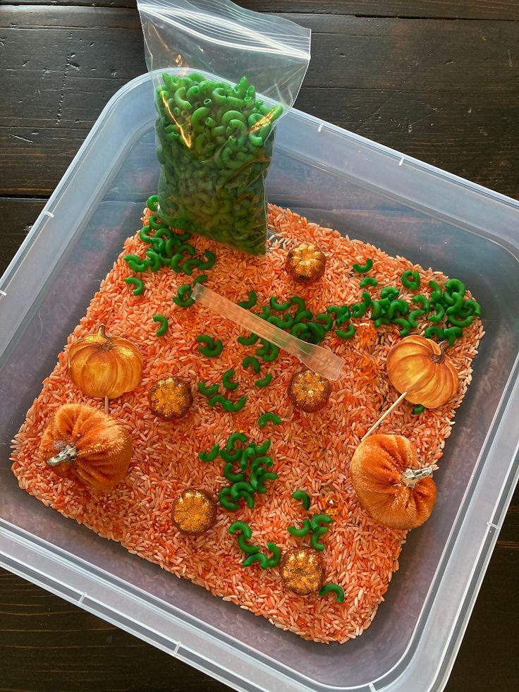 a plastic container filled with carrots and green beans on top of an orange rice krispy kreme