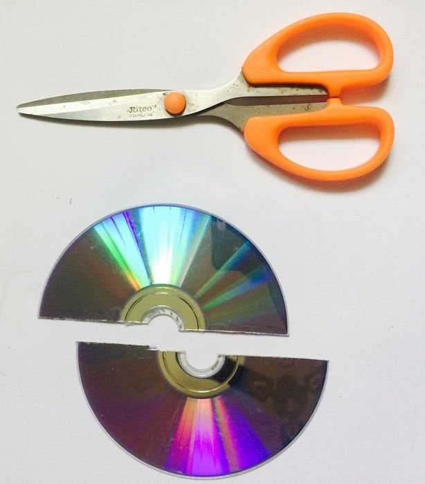 an orange pair of scissors next to a cd