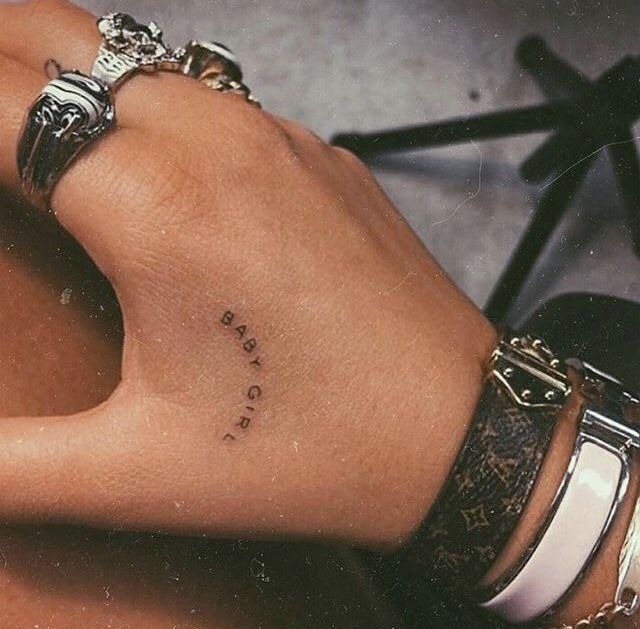 a woman's hand with a small tattoo on her left wrist and the words love is written in cursive writing