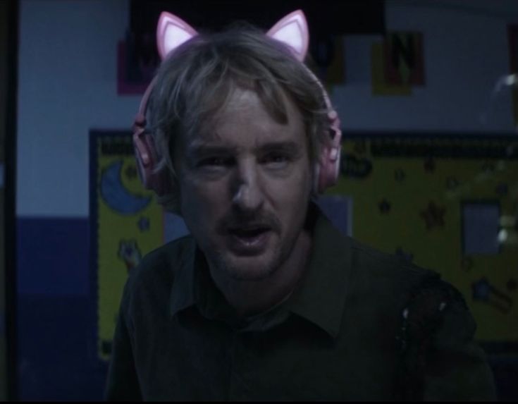 a man with cat ears on his head looking at the camera in a dark room