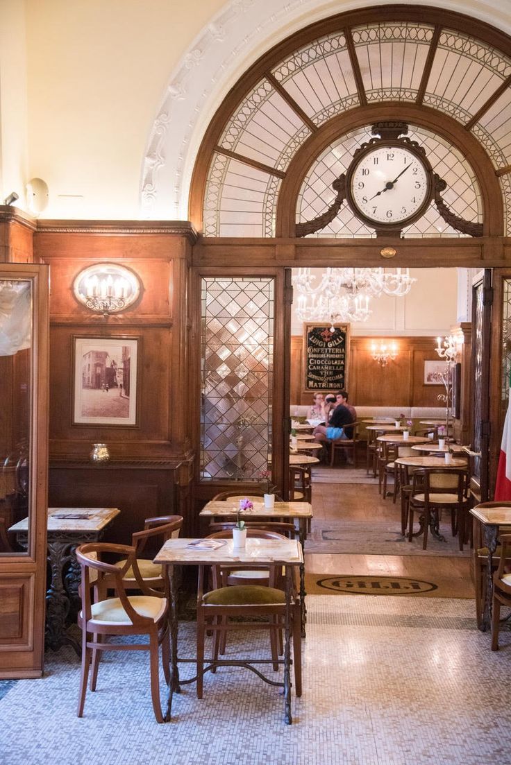 the inside of a restaurant with many tables and chairs in front of a large clock