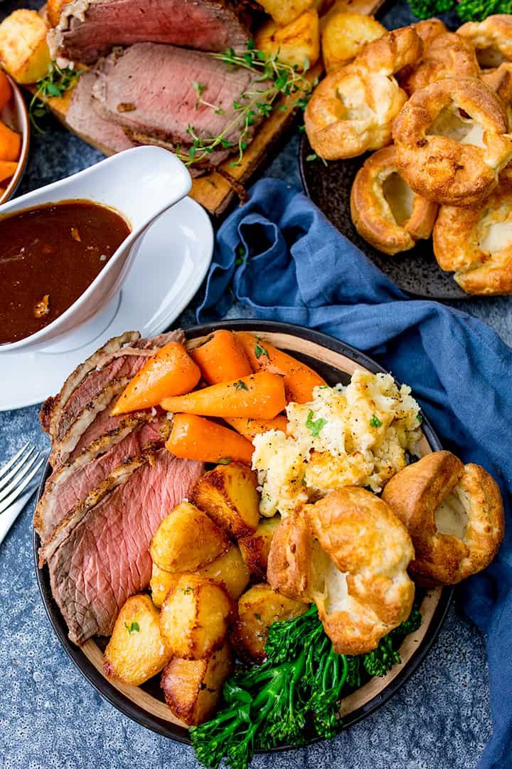 roast beef, potatoes and carrots on a plate with gravy in the background