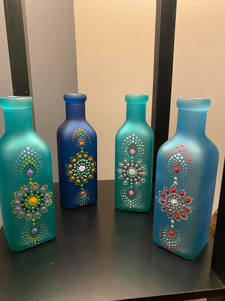 three blue vases with beaded designs on them are sitting on a black table