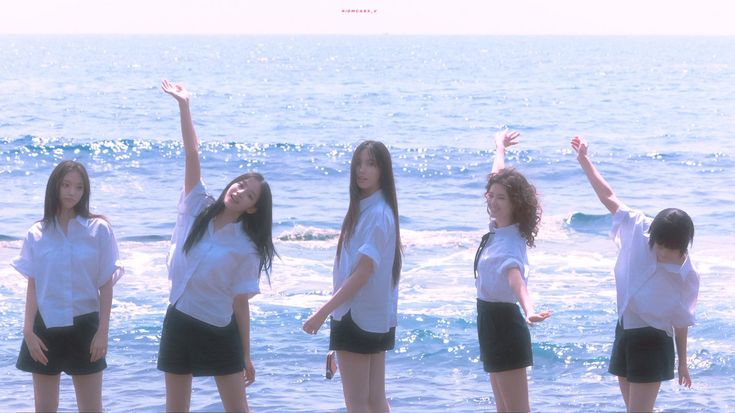 four girls standing in the water with their arms up and one girl raising her hands