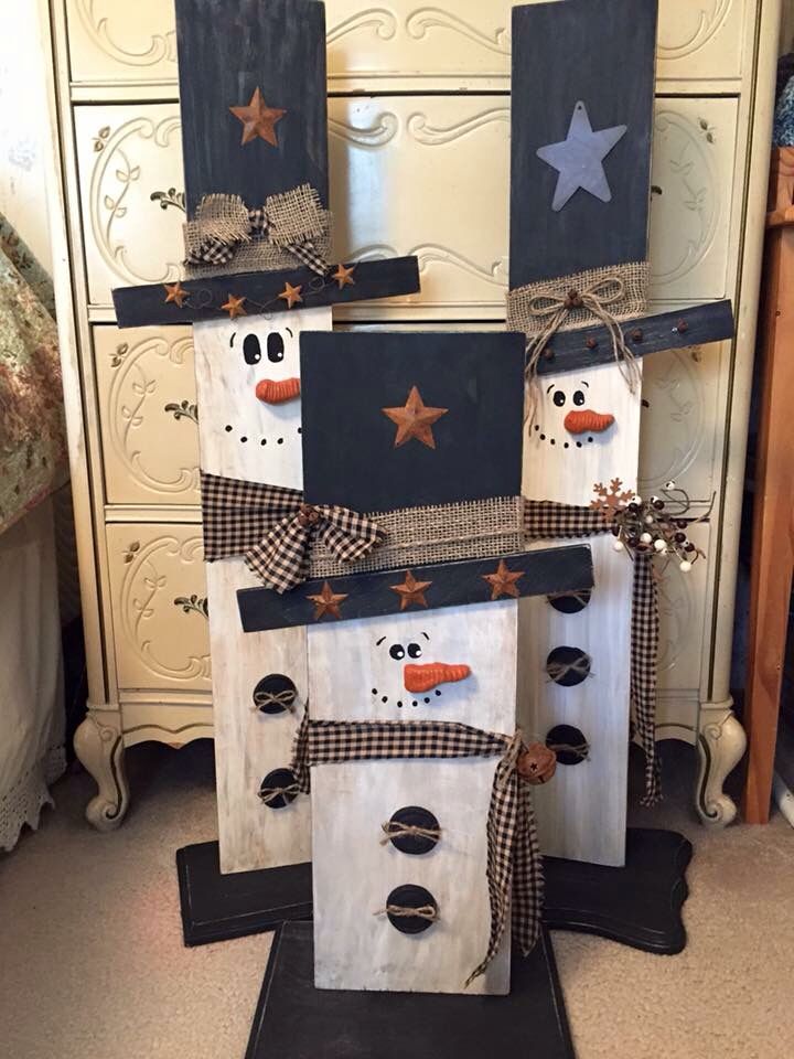 three snowmen made out of wooden boards with stars on them