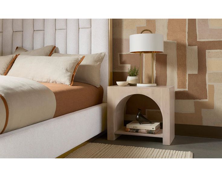 a bedroom with a bed, nightstand and lamp on the side table in front of it