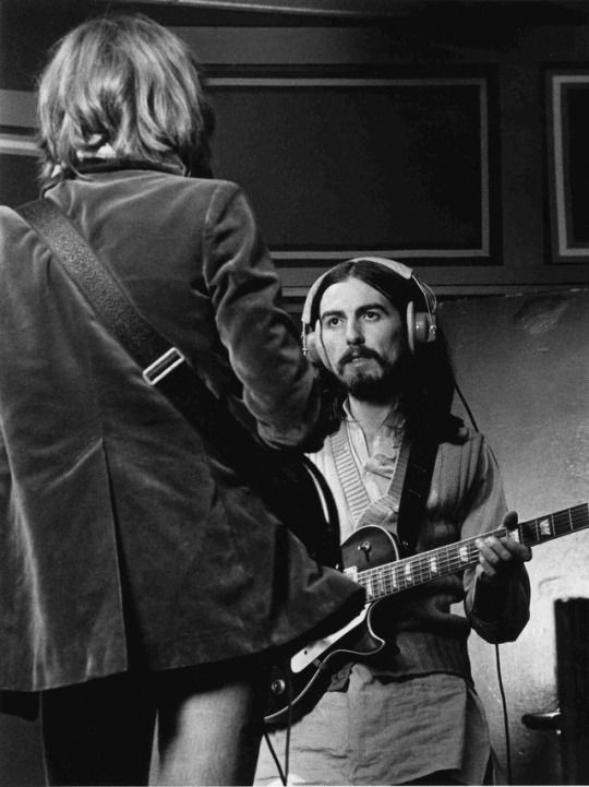 an old photo of a man with headphones on playing guitar and another person standing next to him