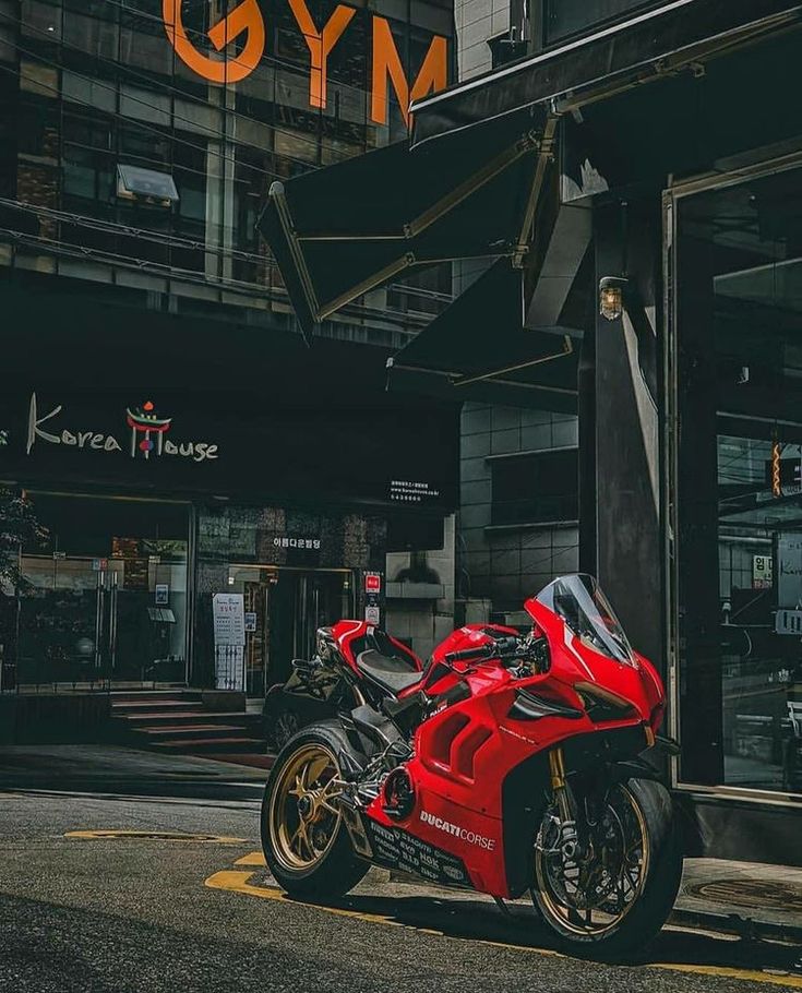 a red motorcycle parked in front of a building