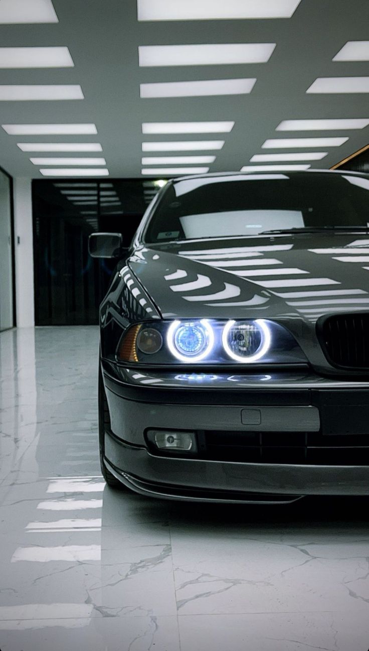 a black car parked in a parking garage with its lights on and the hood up