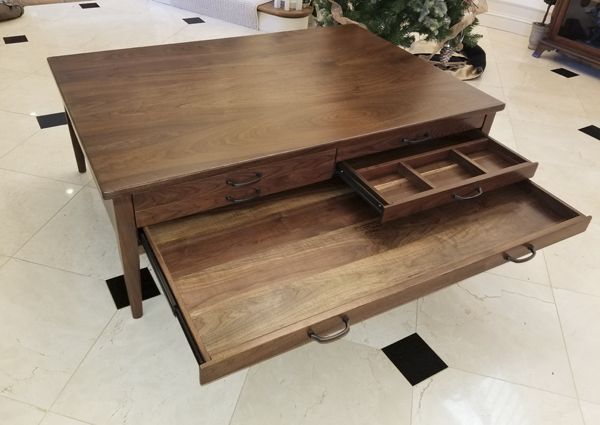 a wooden table with drawers on it in the middle of a floored room,