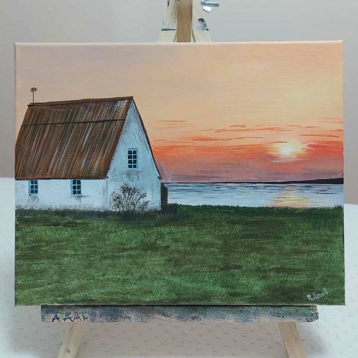 an easel with a painting of a house on it and the sunset in the background