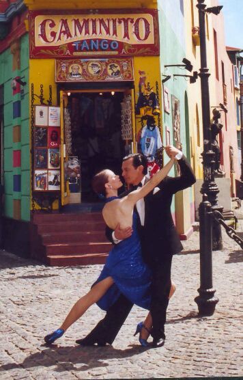 a man and woman dancing in front of a store on a cobblestone street