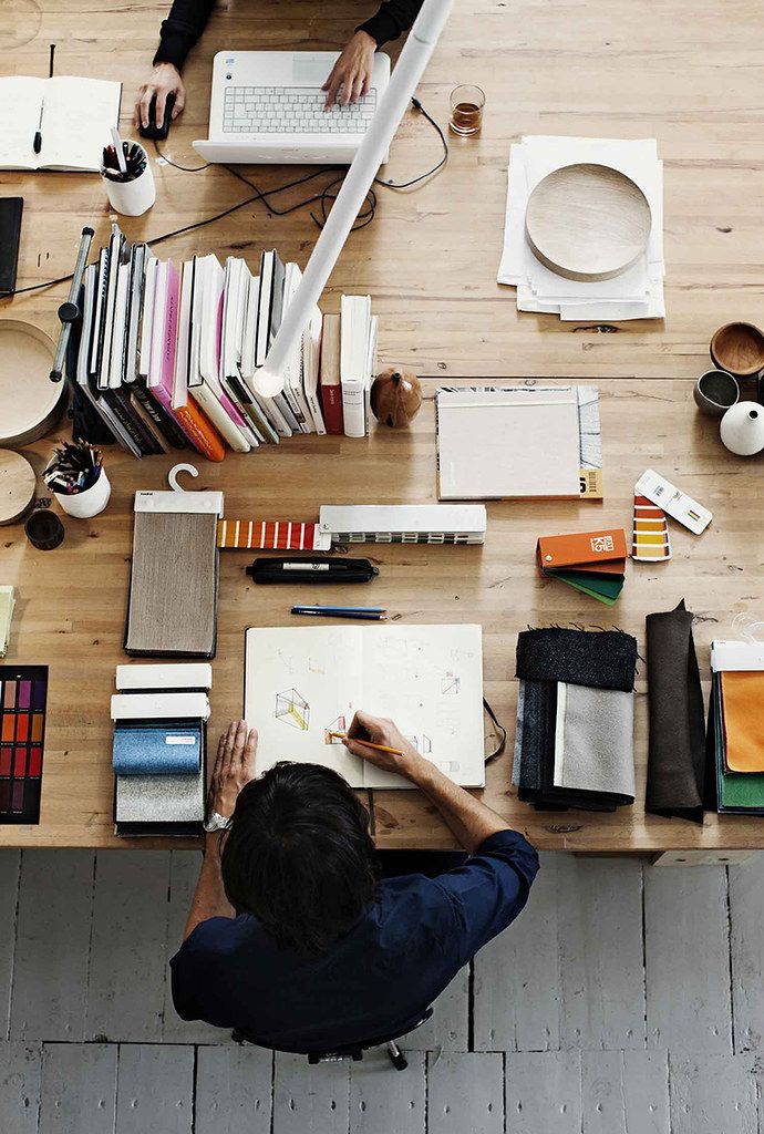 two people sitting at a table with books and laptops