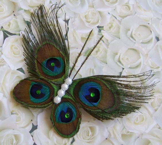 three peacock feathers on top of white roses with pearls in the center and green eyes