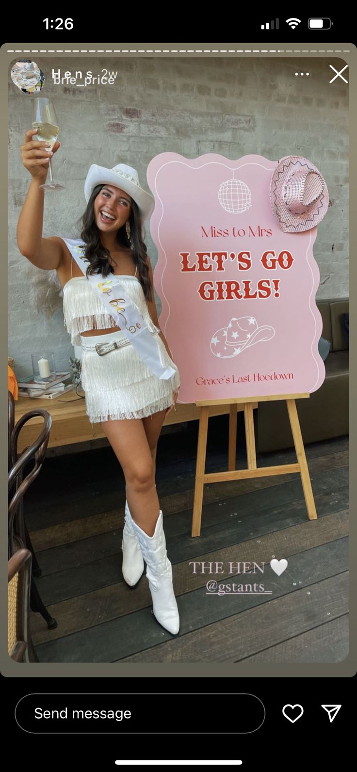 a woman in white dress and cowboy hat holding up a sign that says let's go girls