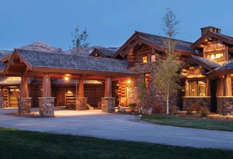 a large stone and wood house with lights on it's front entrance at night