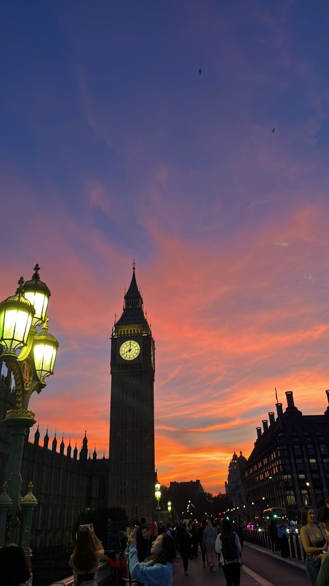 the big ben clock tower towering over the city of london at sunset with people walking around