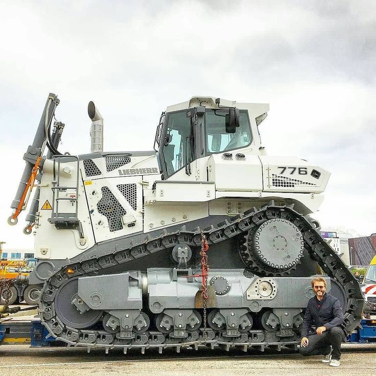 a man sitting next to a large white and black bulldozer