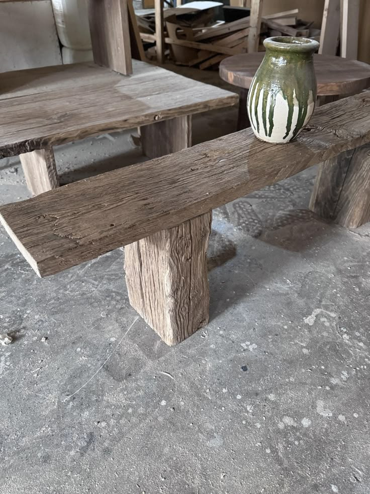 a wooden bench with a vase sitting on top of it