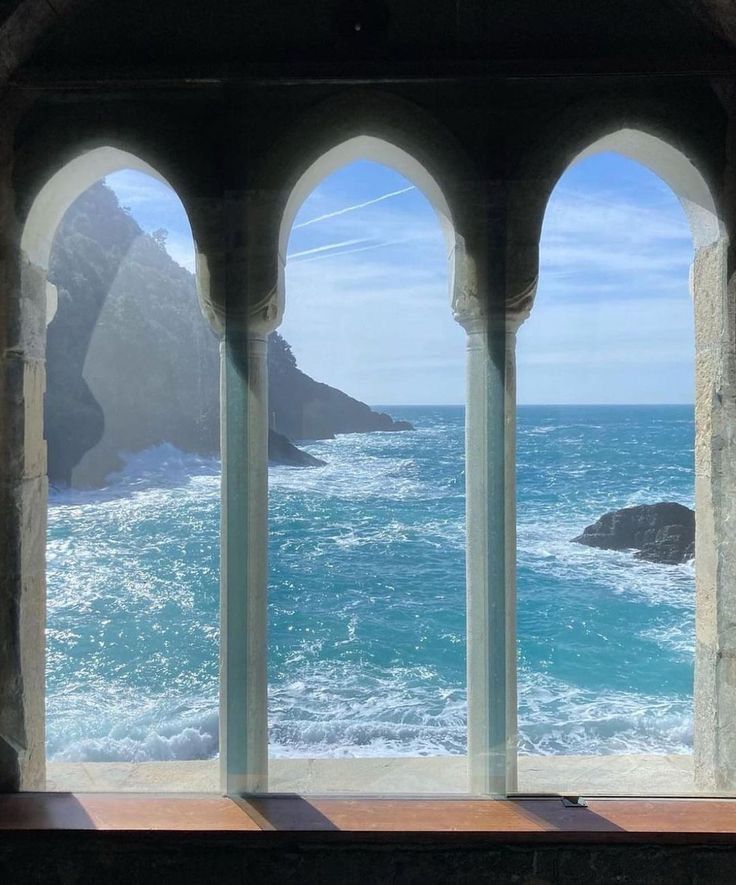 an arched window overlooking the ocean and mountains