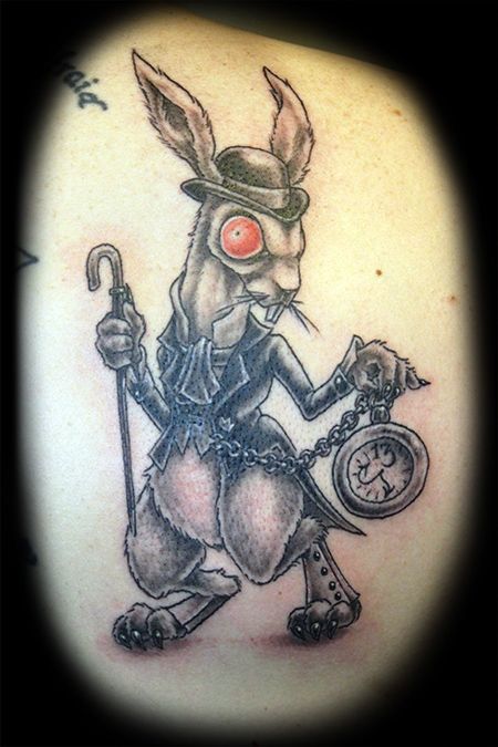 a rabbit with an umbrella and clock tattoo on his back shoulder, holding a cane