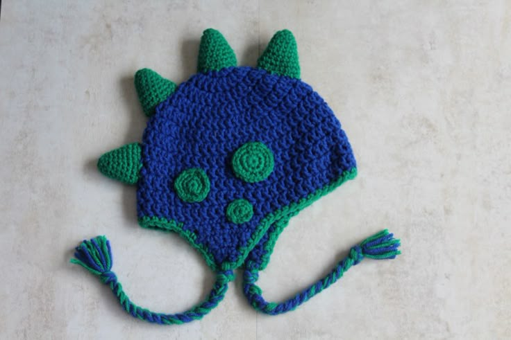 a crocheted blue and green hat with horns on it's head sitting on a white surface