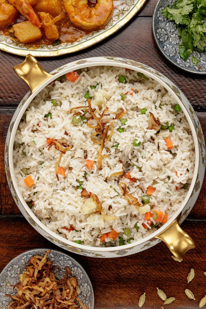 rice with shrimp and carrots in a pan on a table next to other dishes