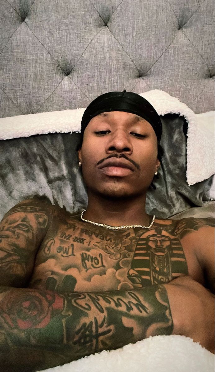 a man laying in bed with tattoos on his chest