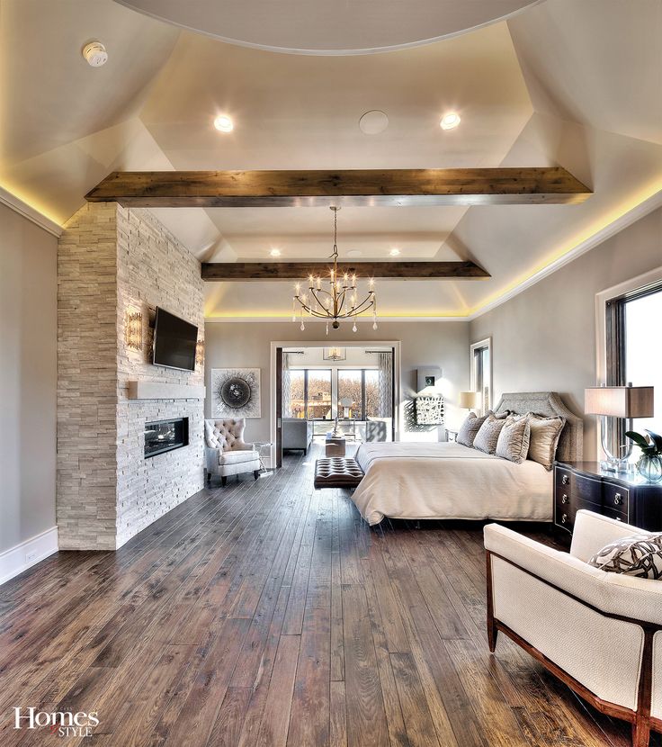 a large bedroom with wood floors and white walls, along with a fireplace in the center