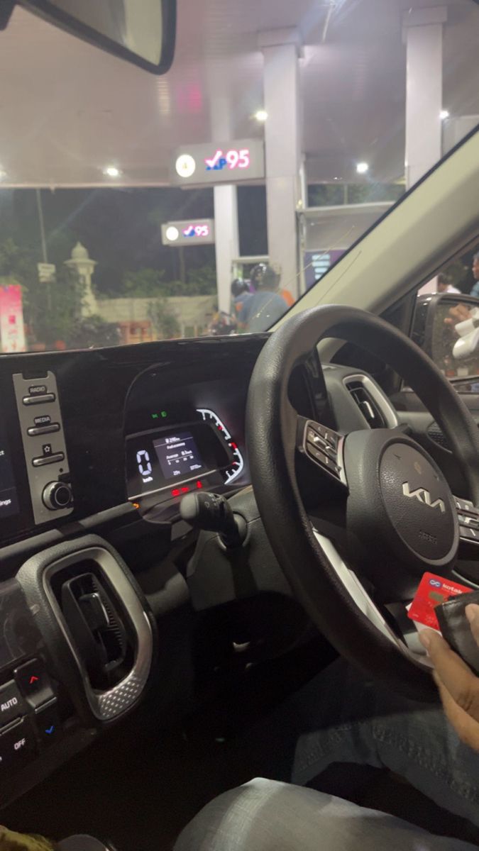 a man sitting in the driver's seat of a car with his hand on the steering wheel