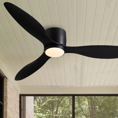 a black ceiling fan sitting on top of a wooden floor next to a large window