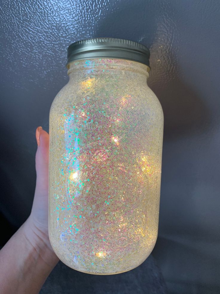 a hand holding a mason jar with holographics on it