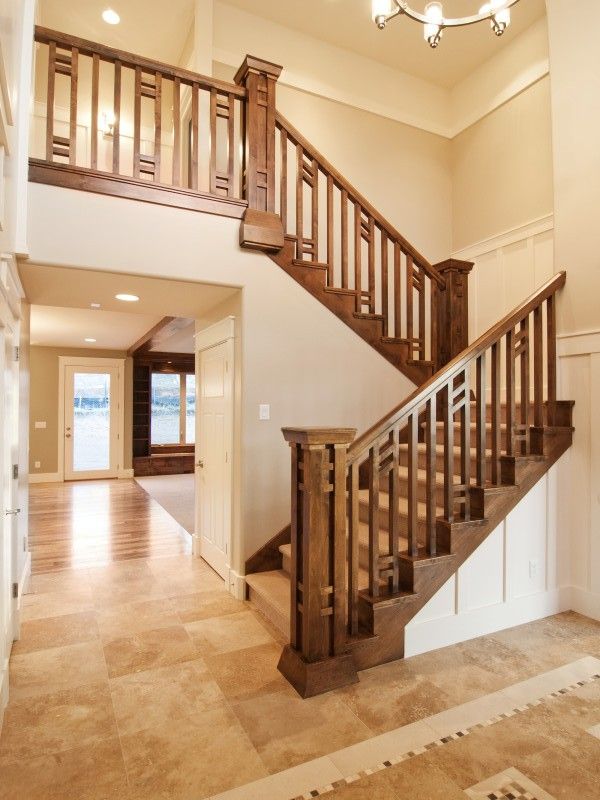 a staircase in a house with tile flooring and white walls, leading to the second floor