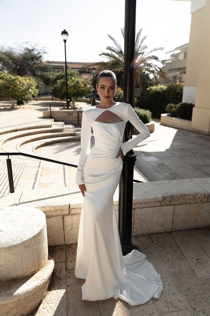 a woman in a white dress standing next to a pole