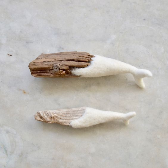 two pieces of driftwood with white fur on them sitting on a marble surface next to each other