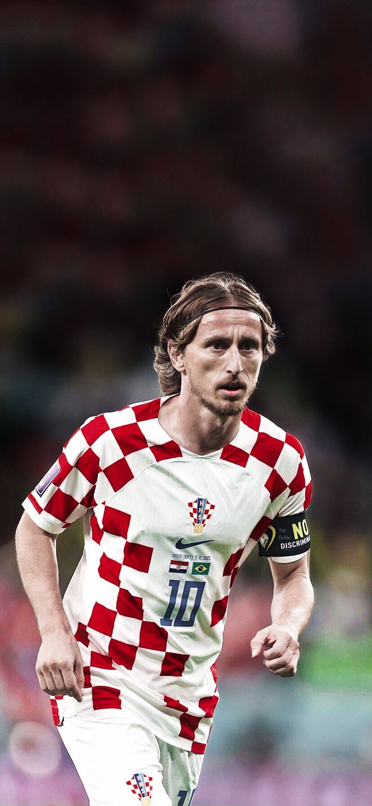 a soccer player is running with the ball in his hand while wearing a red and white checkered shirt