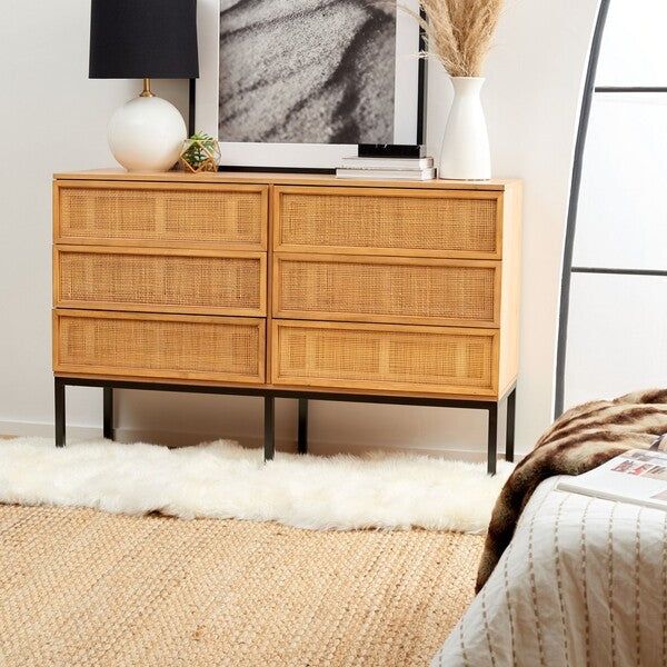 a bedroom with a bed, dresser and pictures on the wall