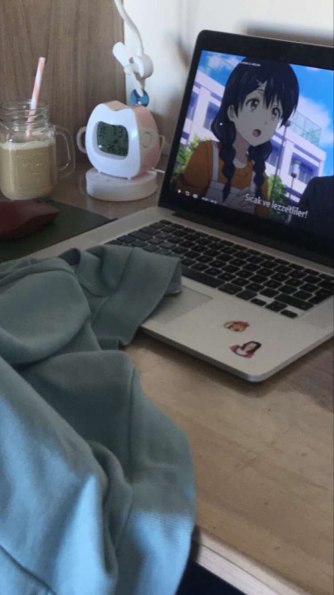 an open laptop computer sitting on top of a wooden desk next to a cup and pen