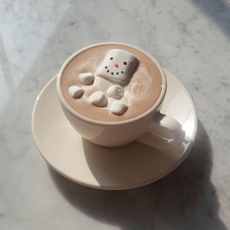 a cup of hot chocolate with marshmallows in the shape of a snowman