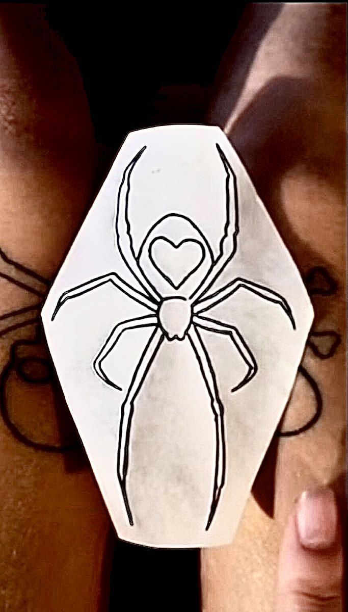 a person holding up a paper cut out with a spider on it's back