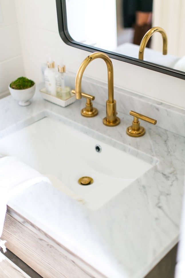 a bathroom sink with gold faucet and marble counter top