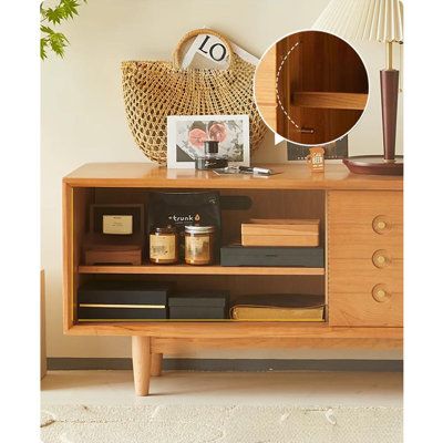 a sideboard with some books and other items on it next to a lamp, mirror and clock