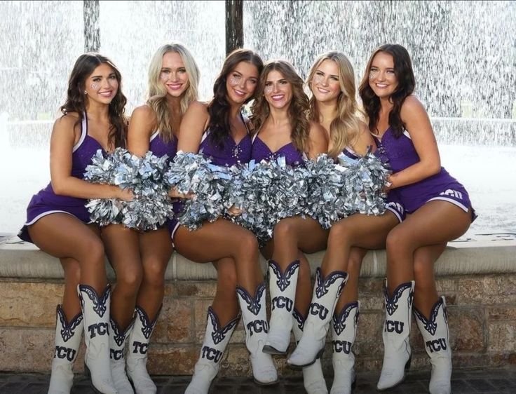 the cheerleaders are posing for a photo in front of a fountain wearing cowboy boots