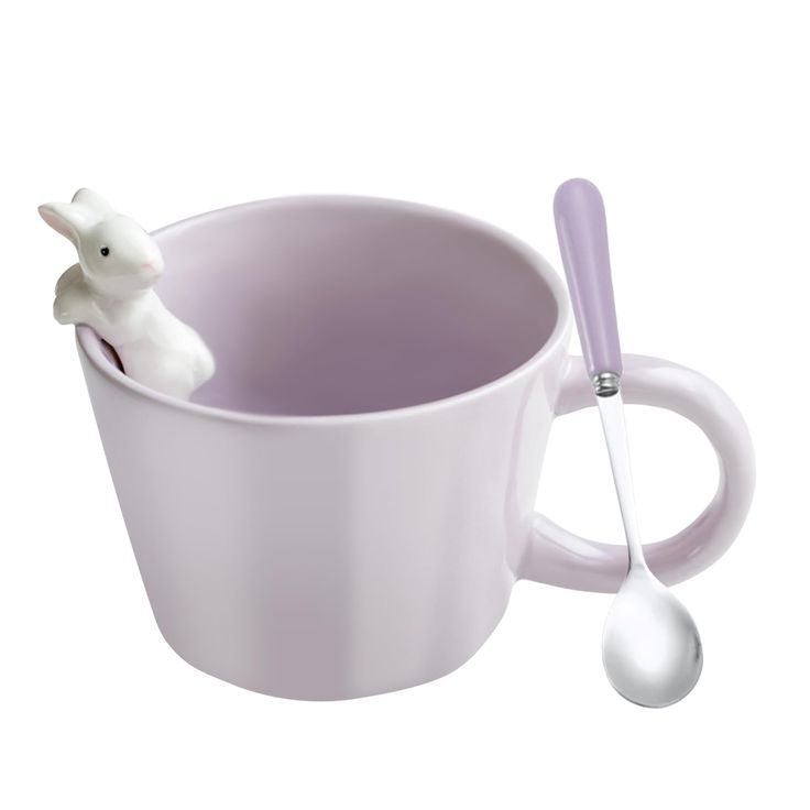 a cup with a spoon in it and a bunny figurine on the side