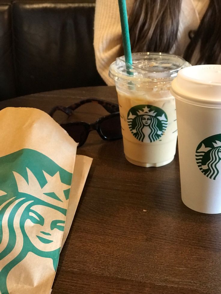 two starbucks drinks sitting on top of a wooden table