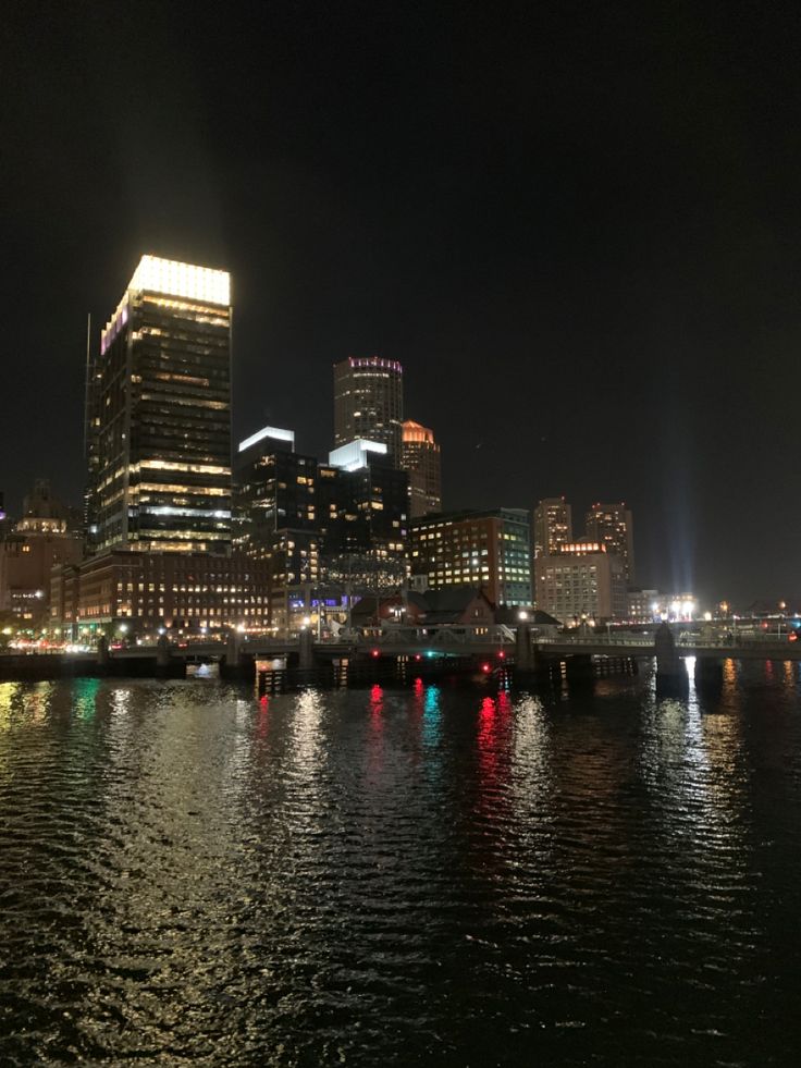 the city is lit up at night with lights reflecting in the water and buildings on both sides