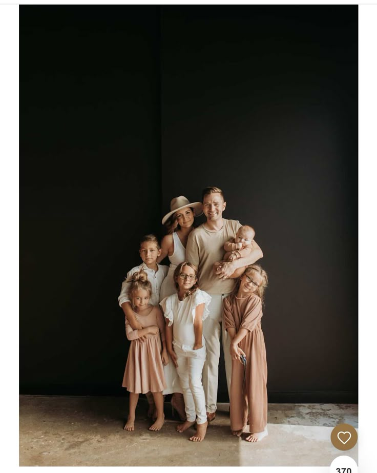 a family posing for a photo in front of a black wall