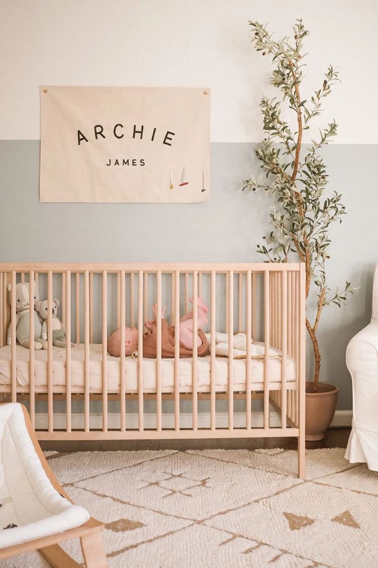 a baby's room with a crib, rocking chair and tree in the corner